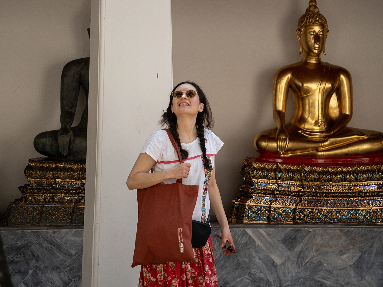Viajera sonriendo frente a un Buda dorado en un templo de Bangkok